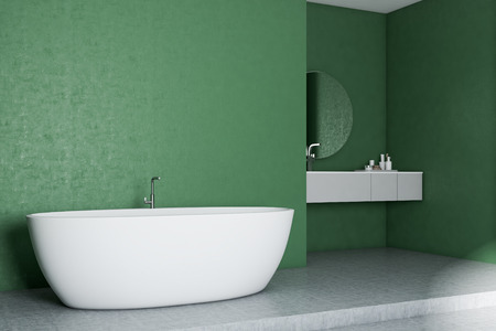 Modern bathroom corner with green walls, concrete floor, white bathtub and a sink with round mirror. 3d renderingの写真素材