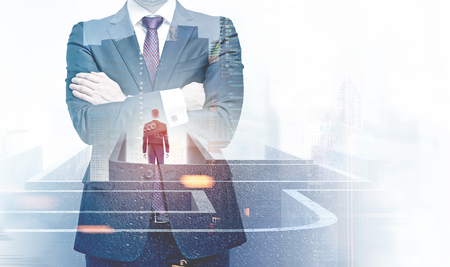 Crossed arms man in checkered tie standing over blurred city background. Businessman lost in maze double exposure. Wrong decision taking concept. Toned image mock upの写真素材