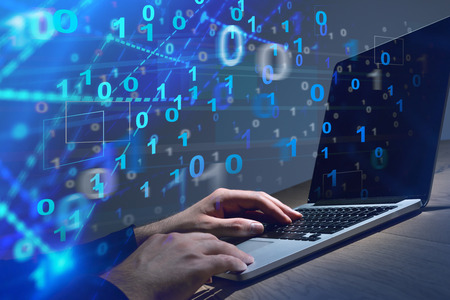 Businessman using his laptop in office. Binary numbers emerging from it. Hi tech concept. Toned...