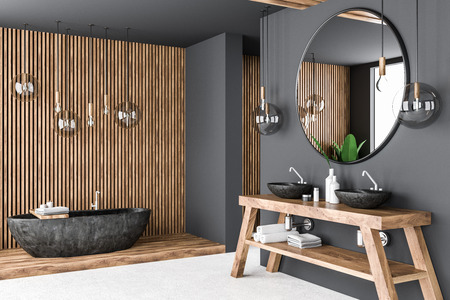 Corner of gray and wooden bathroom with white floor, black bathtub and double sink on countertop with round mirror above it. 3d renderingの写真素材