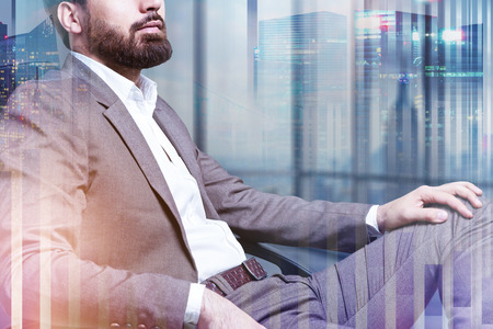 Unrecognizable businessman sitting in his office with night cityscape background. Concept of...