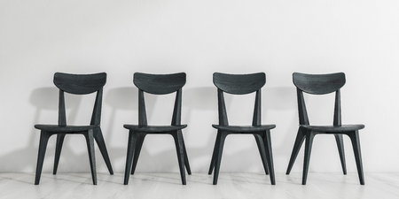 Row of black wooden dining room chairs standing on white wooden floor near white wall. Concept of waiting. 3d renderingの写真素材