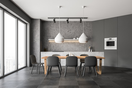 Interior of modern kitchen with concrete walls, tiled floor, gray cupboard with built in oven and concrete countertops. Wooden table with chairs. 3d renderingの写真素材