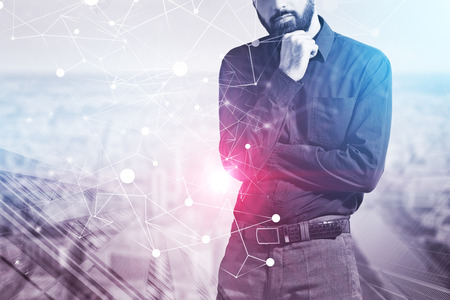 Pensive bearded businessman standing over skyscraper background with double exposure of network hologram. Toned imageの写真素材