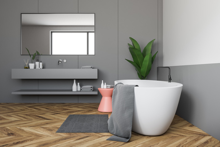 Side view of bathroom interior with white and gray walls, wooden floor, white bathtub and gray sink with horizontal mirror above it. 3d renderingの写真素材