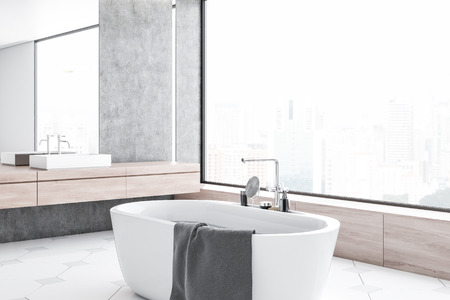 Corner of modern bathroom with concrete walls, tiled floor, panoramic window, white bathtub and white sink with vertical mirror above it. 3d renderingの写真素材