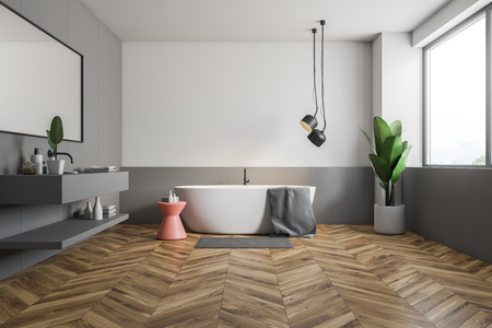 Interior of stylish bathroom with white and gray walls, wooden floor, white bathtub with pink chair near it and gray sink with horizontal mirror. 3d renderingの写真素材