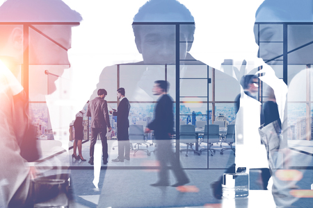 Silhouettes of managers working in office with double exposure of their business team members in office meeting room. Toned image blurredの写真素材