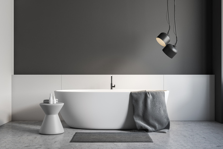 Minimalistic bathroom interior with gray and white walls, concrete floor, white bathtub with gray towel on it and gray chair. 3d renderingの写真素材