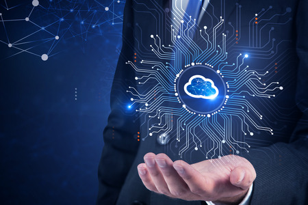 Unrecognizable businessman in dark suit and blue tie holding cloud computer interface hologram. Dark...