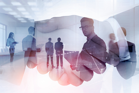 Two businessmen shaking hands with double exposure of business people and graph in the foreground. Toned imageの写真素材