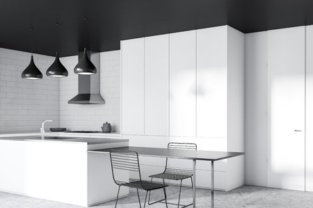 Corner of modern kitchen with white brick walls, concrete floor, black ceiling, white countertops and cupboards, gray and white island and black table with chairs. 3d renderingの写真素材