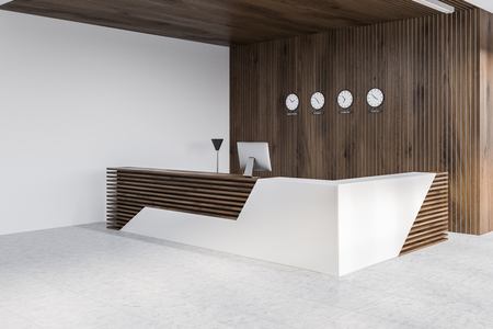 Corner of modern office with white and wooden walls, tiled floor and white and wooden reception desk with computer and clocks on the wall. 3d renderingの写真素材