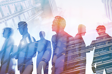 Silhouettes of diverse business team members working together and communicating over city sky and skyscraper background. Toned image double exposureの写真素材