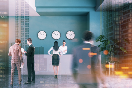 Business people in interior of modern office with dark green walls, concrete floor, gray reception desk with clocks above it and potted plant. Toned image double exposure blurの写真素材