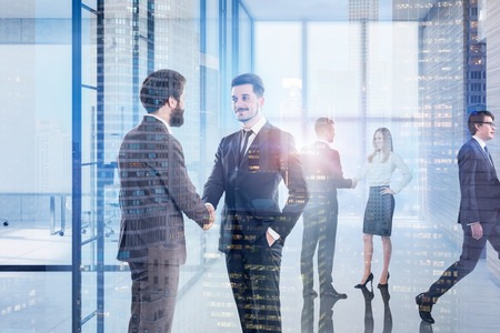 Businessmen and businesswoman shaking hands and communicating in office lobby with double exposure of cityscape. Toned imageの写真素材