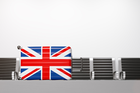 Stylish suitcase with national flag of the United Kingdom lying on airport conveyor belt with chairs in background. Concept of tourism and travelling. 3d renderingの写真素材