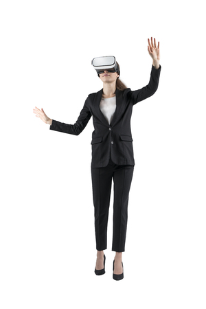 Isolated full length portrait of young businesswoman wearing black suit and VR glasses and gesturing with both hands.の写真素材