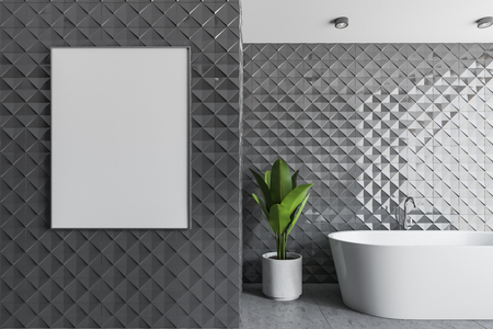 Interior of modern bathroom with gray tile walls, concrete floor, white bathtub and vertical poster frame hanging on the wall. 3d rendering mock upの写真素材
