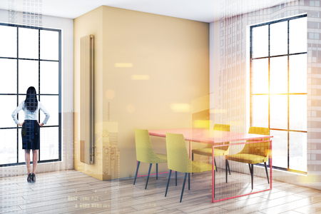 Businesswoman standing in modern dining room with white and yellow walls, wooden floor and pink table with yellow chairs. Toned image double exposureの写真素材