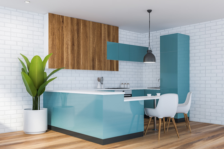 Comfortable kitchen corner with blue and wooden cupboards, blue countertops with sink and cooker and small bar like table with white chairs. 3d renderingの写真素材