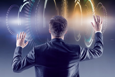 Rear view of man in suit working with futuristic HUD interface. Concept of hi tech in business and digital engineering. Toned imageの写真素材