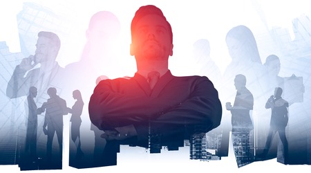 Confident young business leader standing over gray cityscape background with his coworkers shaking hands and talking. Concept of leadership. Toned image double exposureの写真素材