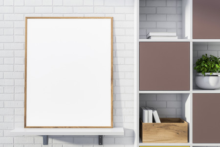 Blank mock up poster with wooden frame standing on white shelf in room with white brick walls and bookcase. Concept of advertising. 3d renderingの写真素材