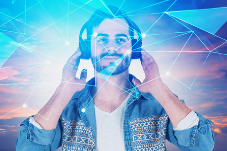 Portrait of handsome young man smiling and listening to music over cloudy sky background. Digital polygons interface. Concept of hi tech. Toned image double exposureの写真素材