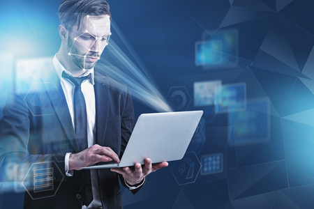 Serious man in suit holding laptop computer with facial recognition and biometric verification technology. Concept of security check and machine learning. Blue background with icons. Double exposureの写真素材