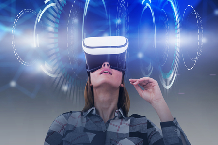 Astonished young woman in checkered shirt and virtual reality headset enjoying her VR experience....