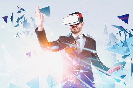 Young businessman wearing suit and VR headset working with network interface over white background. Concept of hi tech and programming. Toned image double exposureの写真素材