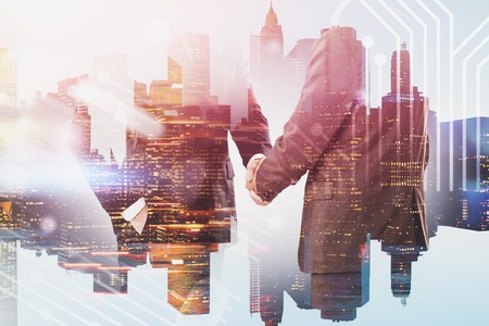 Unrecognizable businessmen shaking hands over cityscape background with circuit interface. Concept of technological startup and partnership. Toned image double exposureの写真素材