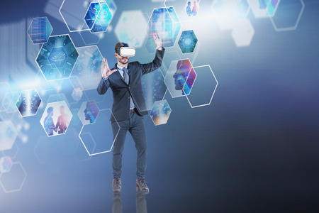 Serious young man in VR headset working with business images. Concept of hi tech in business and engineering. Toned image double exposure. Elements of this image furnished by NASAの写真素材