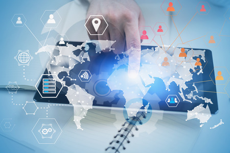 Hand of man using tablet computer on office table with double exposure of global business...