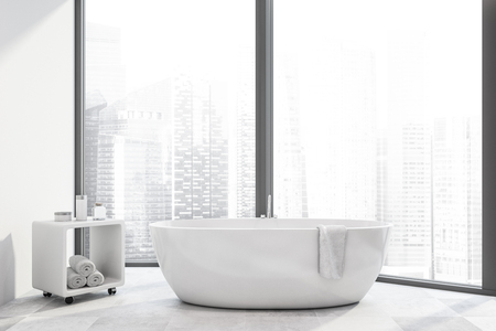 Interior of panoramic bathroom with cityscape, white walls, tiled floor and bathtub with cabinet with towels and creams near it. 3d renderingの写真素材