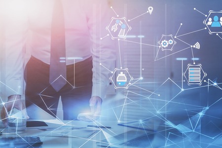 Unrecognizable businessman working with smartphone in white office with double exposure of business interface and network hologram. Toned imageの写真素材