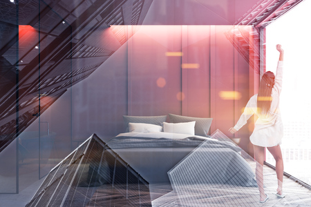 Woman in pajamas standing in modern bedroom interior with red walls, wooden floor and master bed. Bathroom next to it. Toned image double exposureの写真素材
