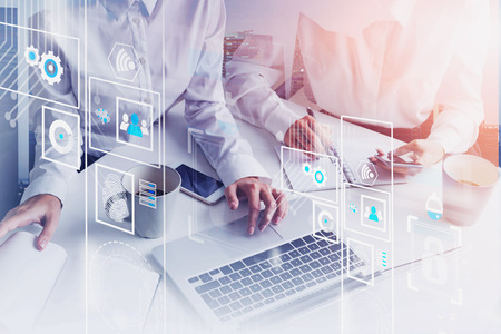 Hands of businesswomen working with gadgets in office with double exposure of city and immersive HUD...