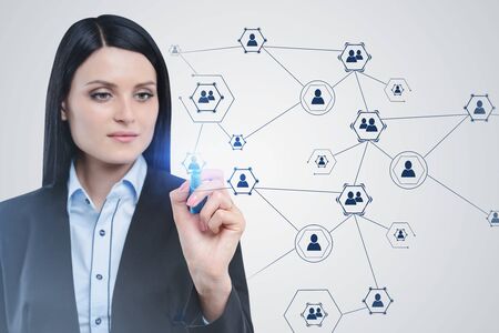Serious beautiful businesswoman with dark hair working with social network interface. Concept of...