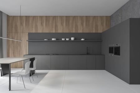 Interior of stylish kitchen with concrete and wooden walls, gray countertops with sink and cooker, gray cupboard with two ovens and table with white chairs. 3d renderingの写真素材
