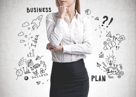 Unrecognizable pensive woman in business suit standing near concrete wall with business plan sketch drawn on itの写真素材