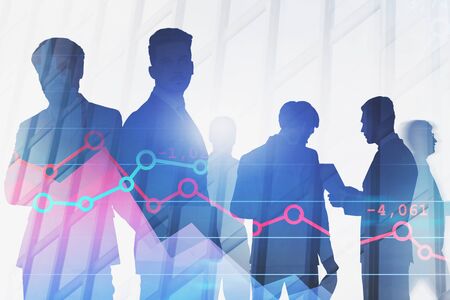 Silhouettes of businessmen working together over skyscraper background with double exposure of graphs. Concept of teamwork and stock market. Toned image blurredの写真素材
