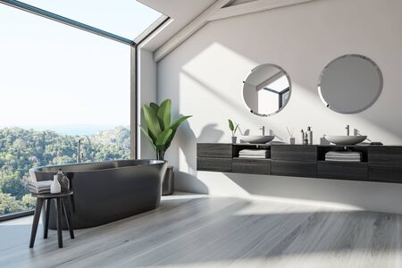 Corner of Scandinalvian style bathroom with white walls, wooden floor, black bathtub and double sink...