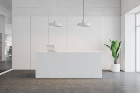 Interior of stylish office with white and brick walls, concrete floor and white reception table with laptop computer on it. 3d renderingの写真素材