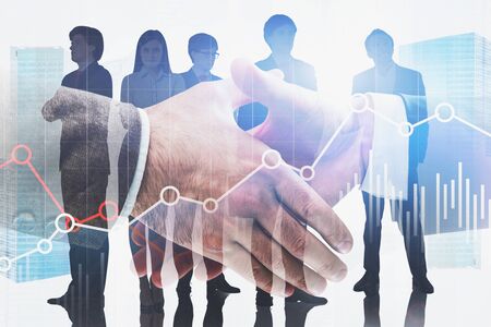 Close up of two businessmen shaking hands in city with double exposure of business team and graphs. Concept of stock market and partnership. Toned imageの写真素材