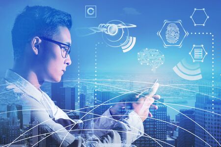 Asian businessman in glasses looking at smartphone in city with double exposure of business...