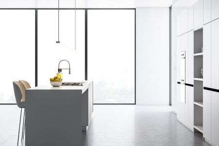 Side view of loft kitchen interior with white walls, concrete floor, white cupboards with built in...