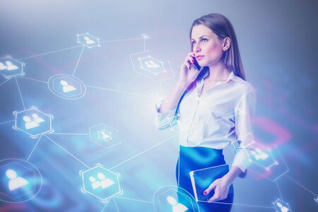 Serious young blonde businesswoman talking on smartphone over gray background with double exposure...