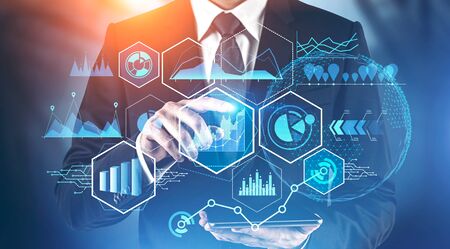 Businessman with tablet working with business infographics interface and digital graphs over blurred...